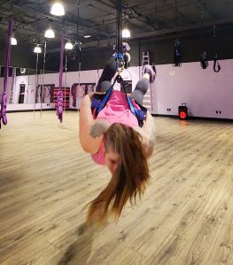 A bungee fitness instructor jumps head first towards the ground in the bungee harness.