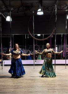 Two individuals perform a belly dance routine at Pole Kisses Holiday Showcase.